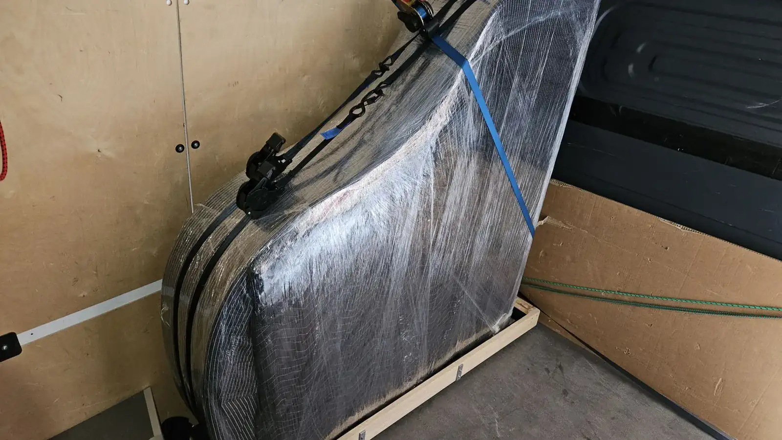Verpackter Flügel auf der Seite im Holzschlitten, mit Spanngurt fixiert