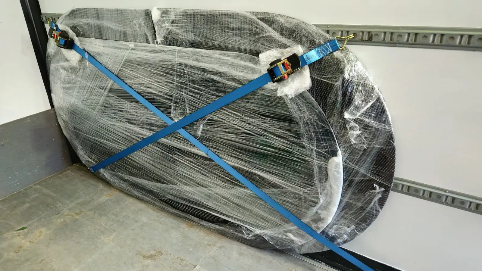 Verpackter Flügel mit gekreuzten Zurrgurten an den Zurrschienen des Laderaums gesichert