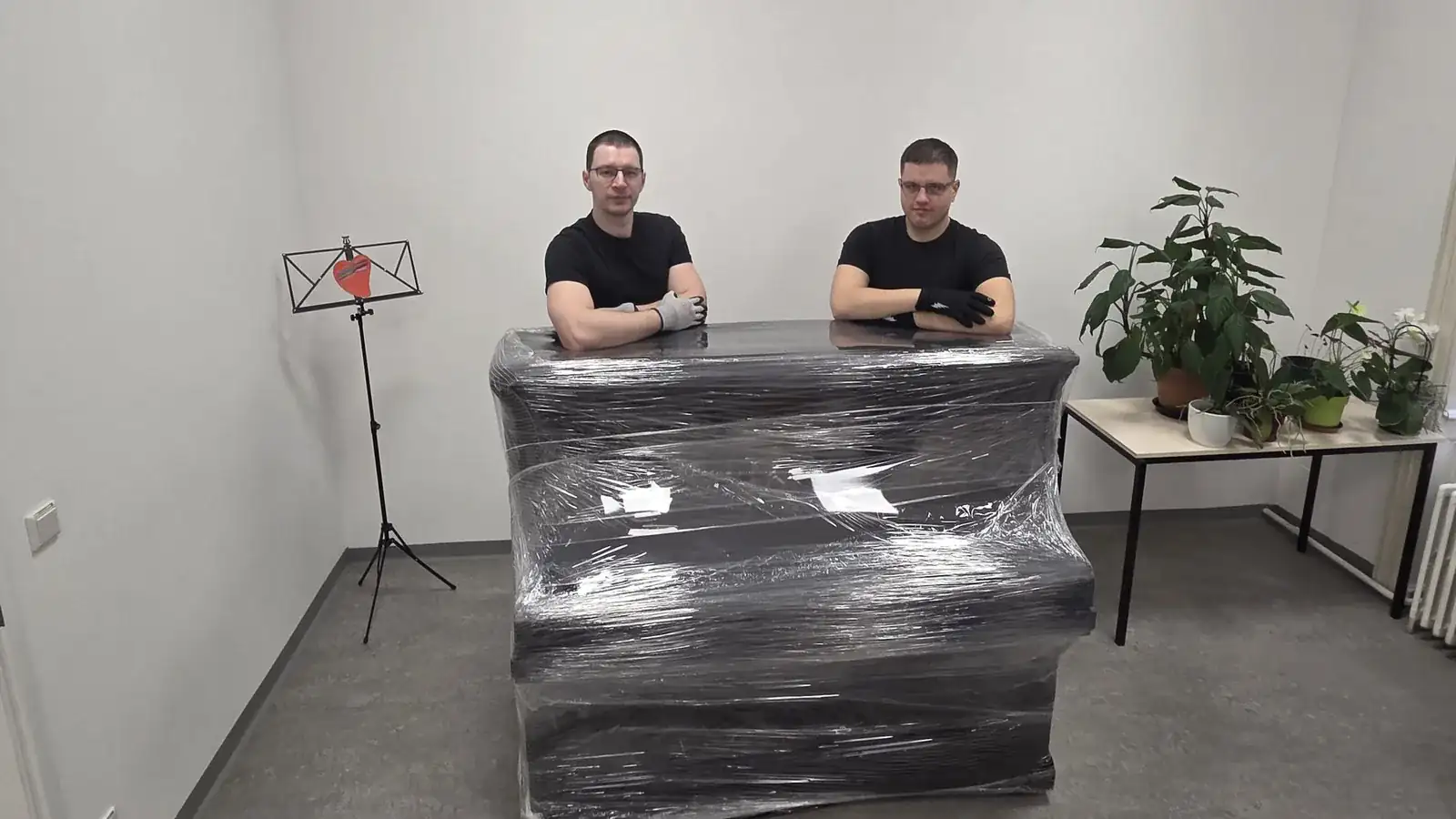 Goran und Josip von FlexiTrans hinter einem verpackten Pianino