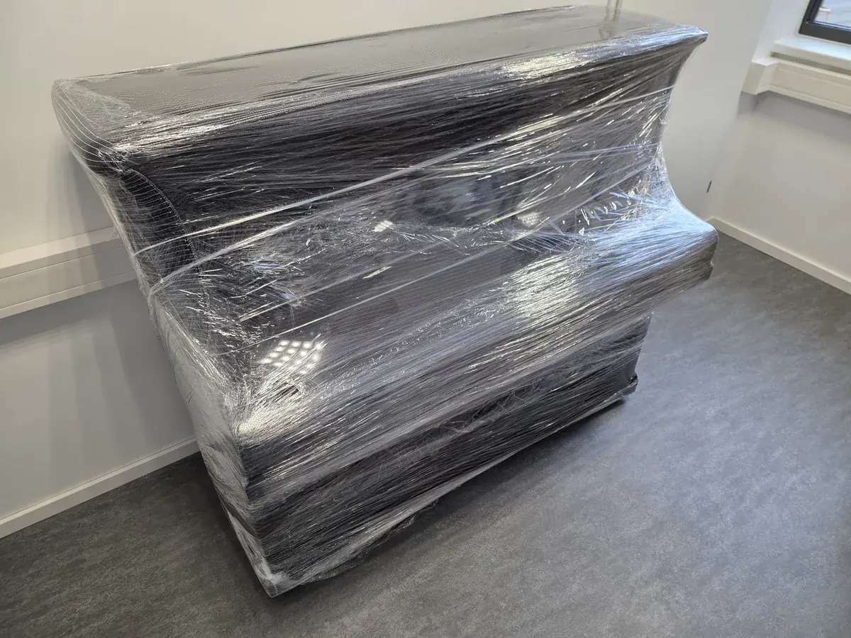 Pianino verpackt und transportbereit im Wohnraum