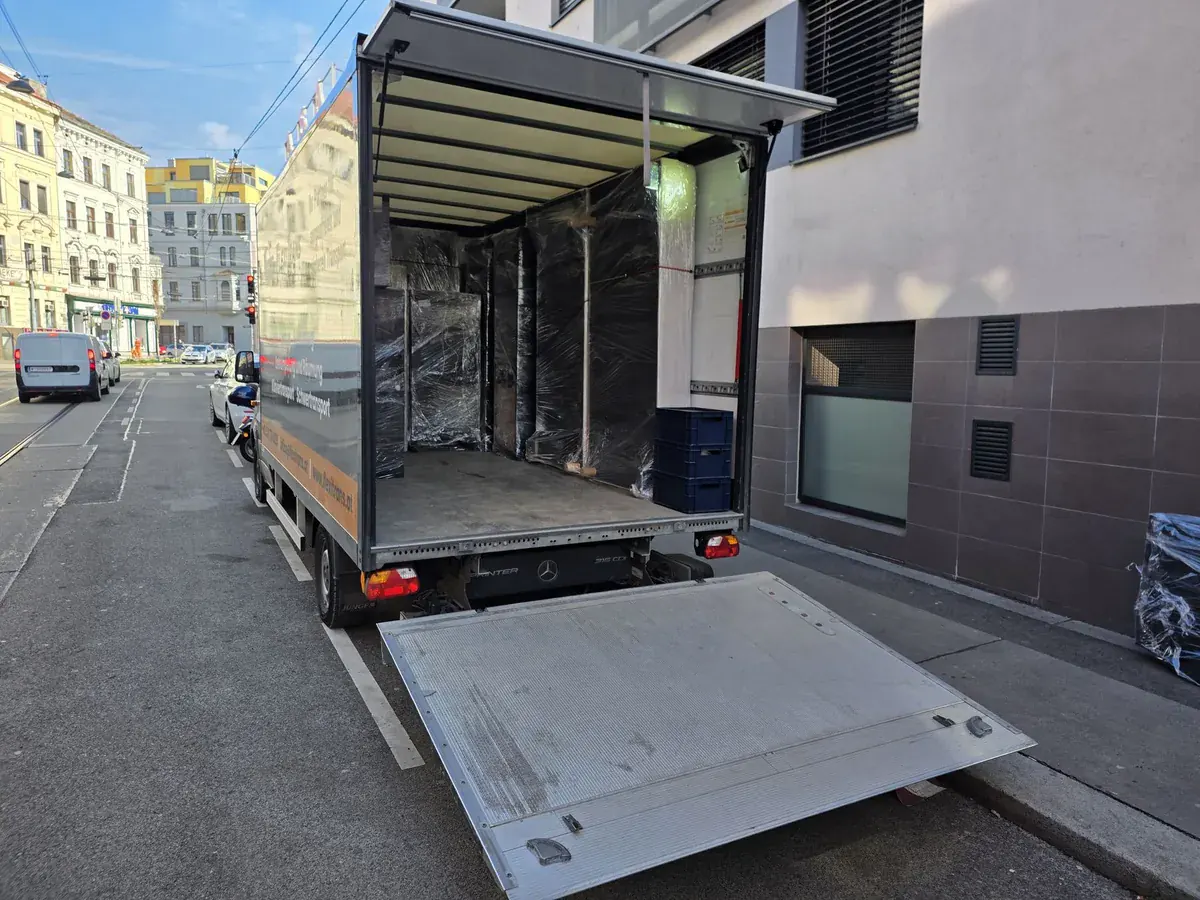 LKW von FlexiTrans mit abgesenkter Hebebühne in einer Wiener Straße